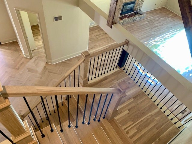Upstairs overlook with oak handrail and iron balusters above a herringbone floor