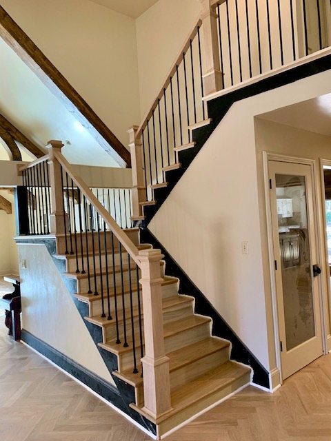 Two-story staircase with oak treads, black skirt board and iron balusters