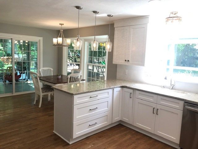 White kitchen remodel with shaker cabinets, a peninsula and pendant lights